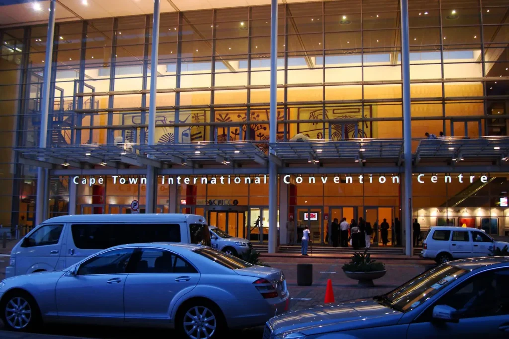 Exterior of the CTICC entrance at night with various motor vehicles. 