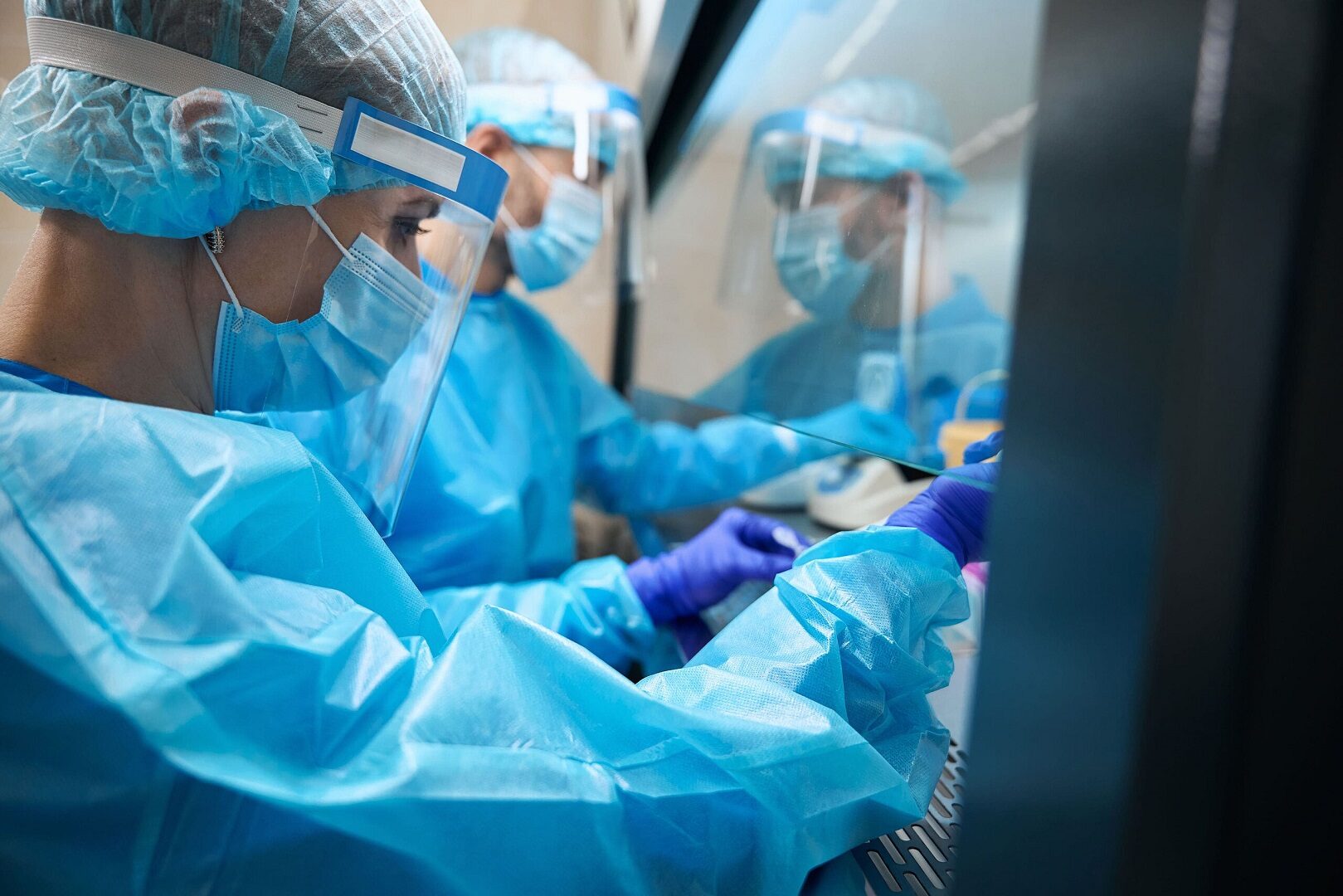 Healthcare workers wearing full blue personal protective gear.