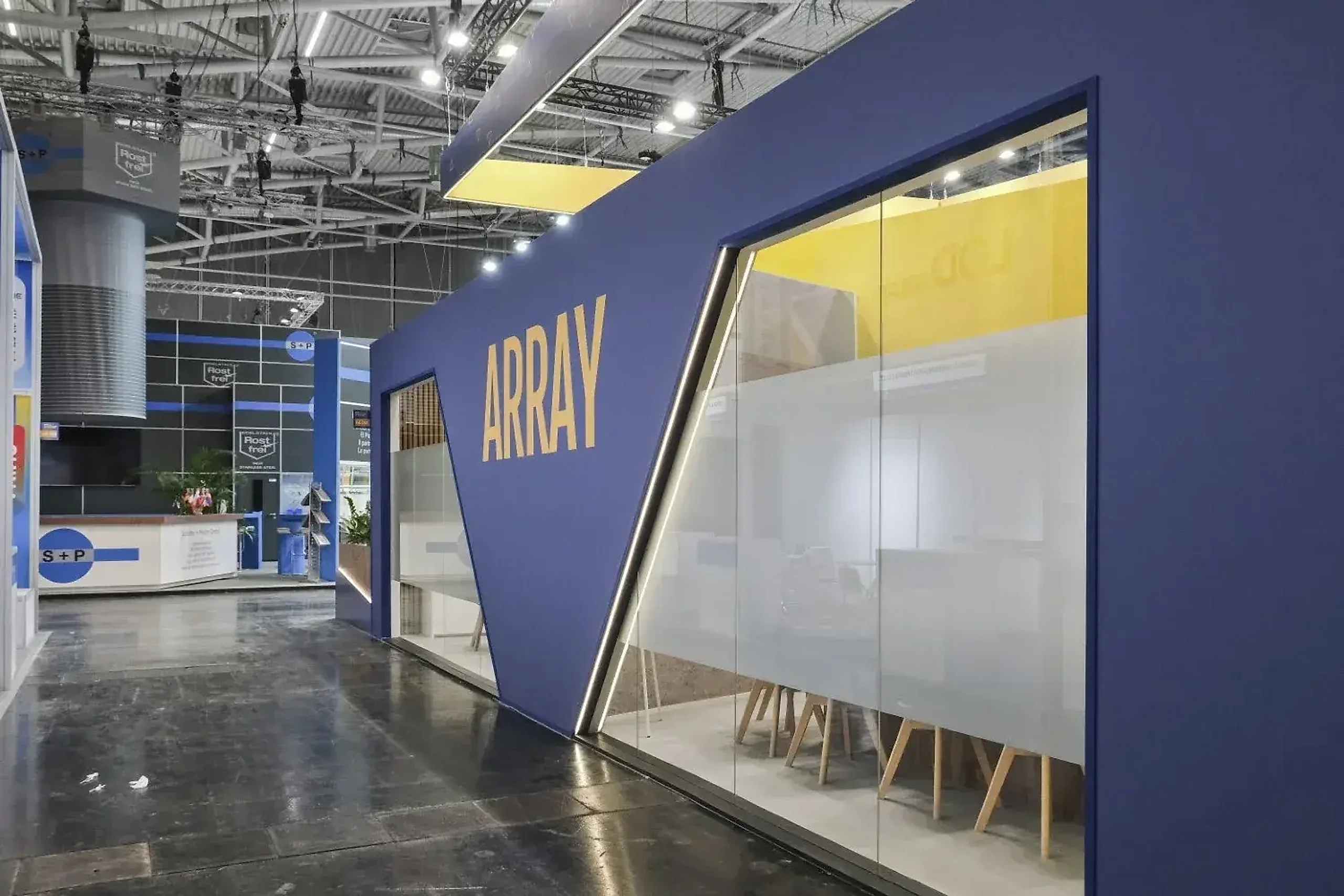 Array exhibition stand in deep blue with an angular cut-away facade and yellow interior