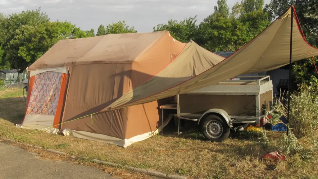 An outdoor tent set up next to a trailer.