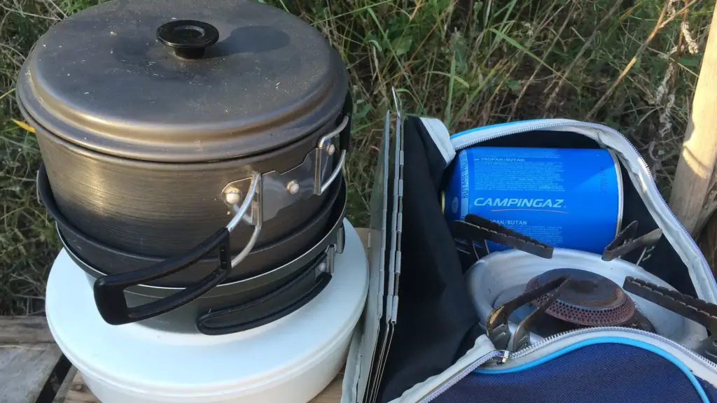 Cooking pots next to a bag containing a camping stove and a gas canister.