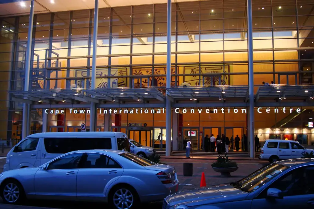 Exterior of the CTICC entrance at night with various motor vehicles.