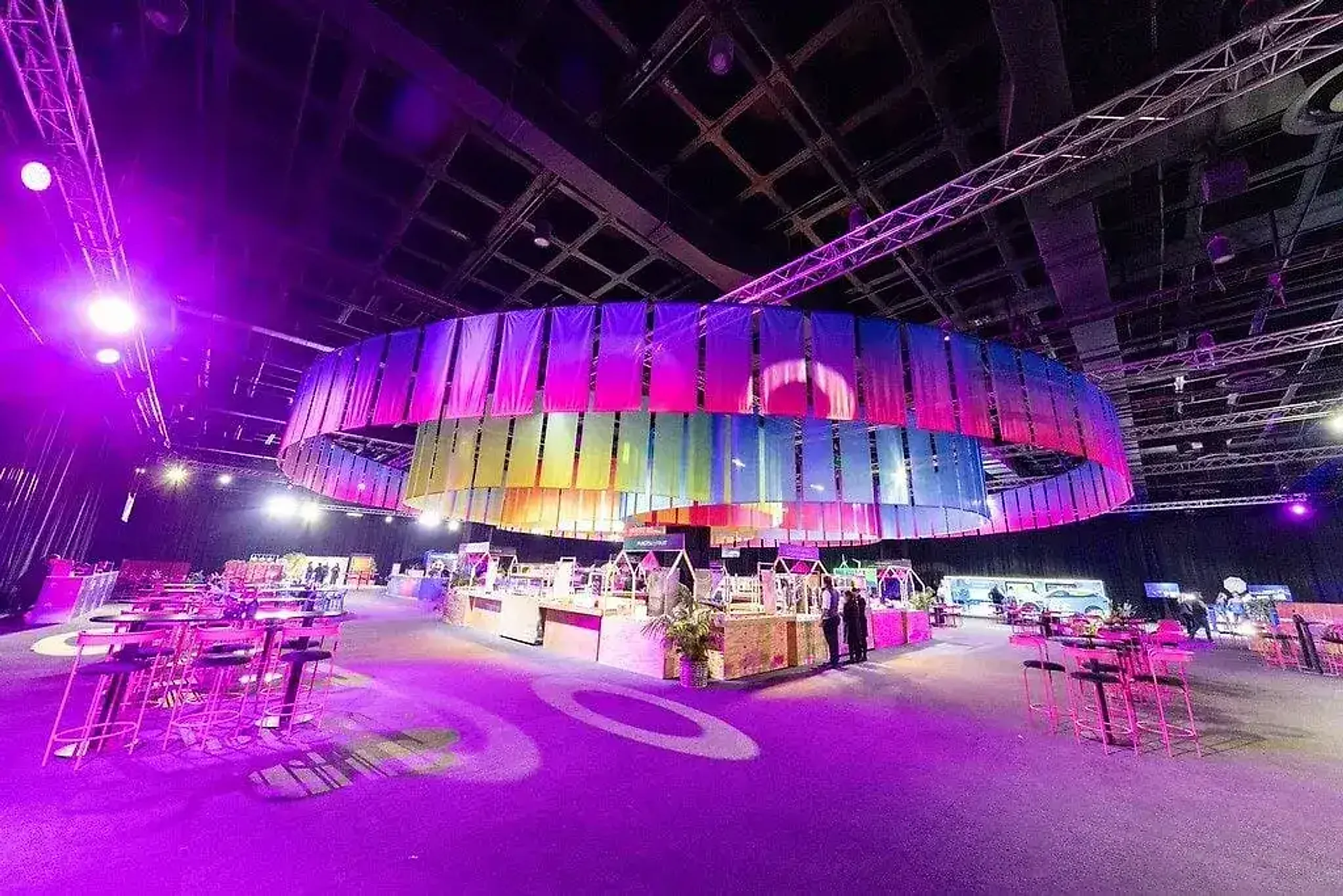 Discovery stand with curved branded walls under saturated stage lighting