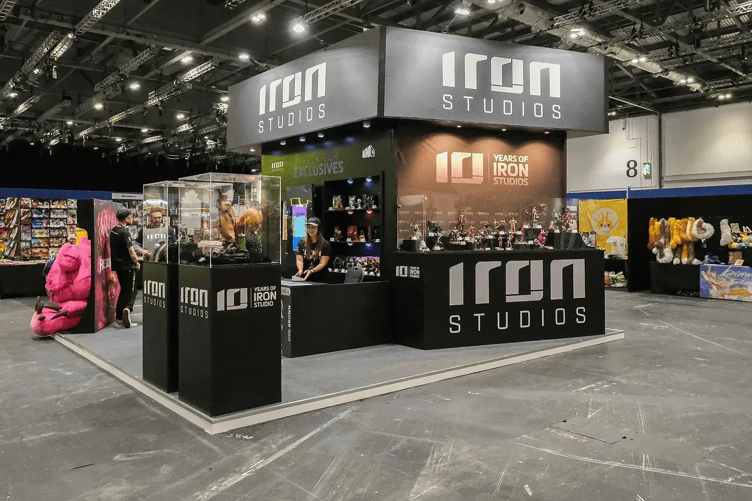 Iron Studios stand with lit display plinths and collectible figures