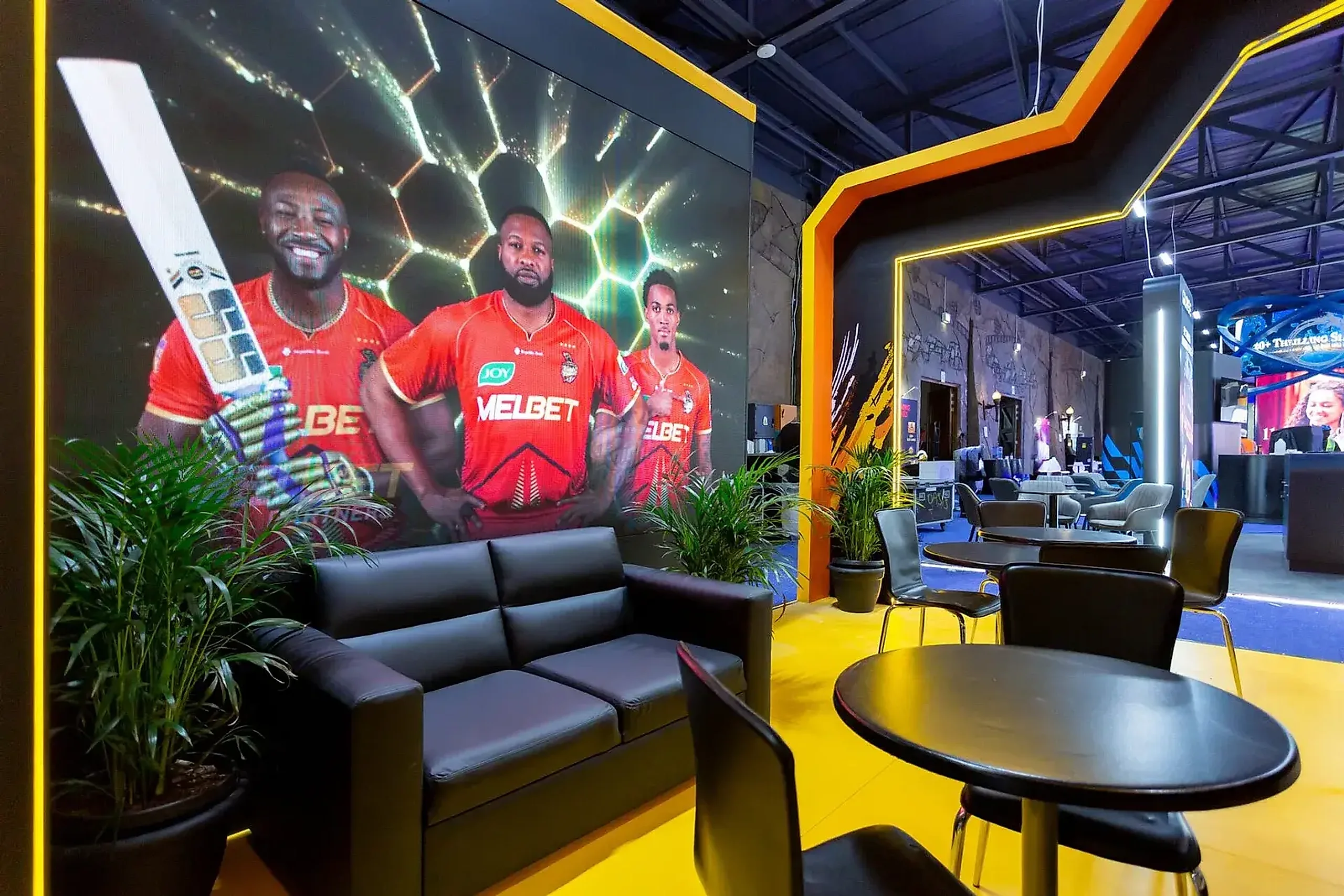Melbet hospitality lounge at SIGMA Africa 2025 with a full-height LED wall and yellow floor