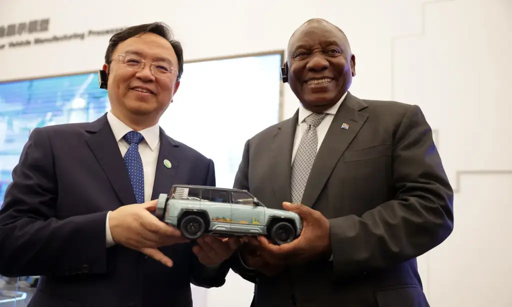 South African President Cyril Ramaphosa smiles and holds a toy car at the BYD facility in China.